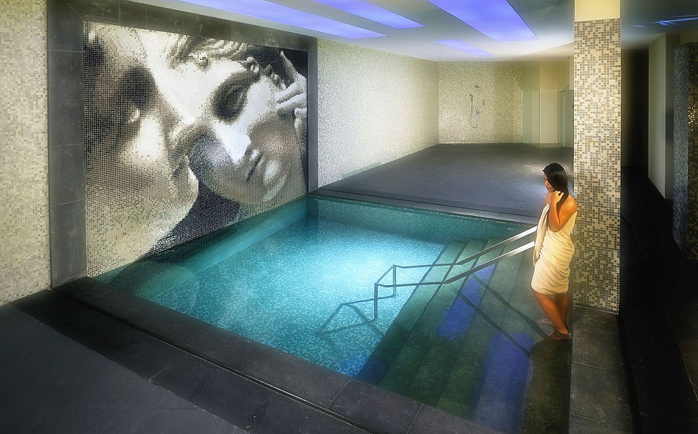 Serene spa pool featuring an elegant mosaic of two faces on the wall and soft blue lighting that enhances the calming atmosphere.