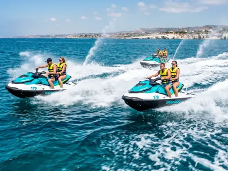 Three jet skis speeding across turquoise water along the Protaras coastline near Cape Greco, kicking up white spray during a guided jet ski tour