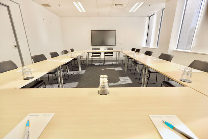 Large meeting room with TV, whiteboard, and natural light