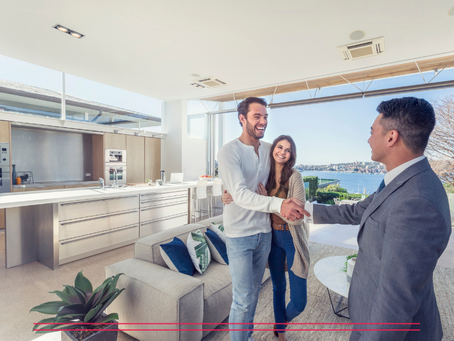 A realtor showing a waterfront condo to a young couple and shaking the man's hand