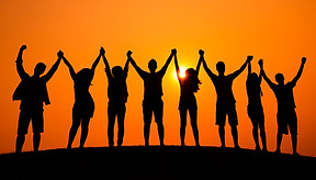 Silhouetted people holding hands at sunset