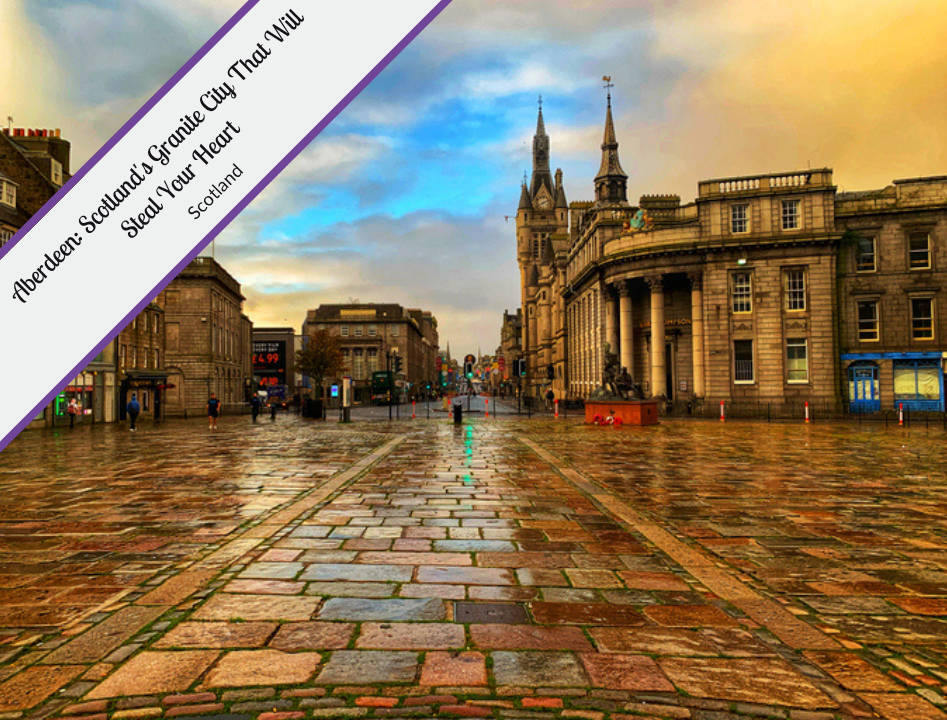 A wide-angle, low-perspective view of the Castlegate in Aberdeen, Scotland, showing a vast expanse of wet, multicolored cobblestones reflecting a dramatic blue and orange sunset sky. In the upper-left corner, a thick diagonal purple banner contains the text: "Aberdeen: Scotland's Granite City That Will Steal Your Heart, Scotland." To the right, the grand granite architecture of the Salvation Army Citadel and its spires rise against the clouds, alongside historic buildings with classical columns. The street is nearly empty, with a few distant figures and city lights beginning to glow on the damp ground.