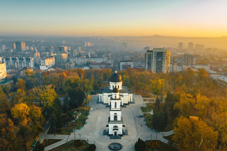 Aerial view of Chisinau city center at sunrise, featuring the Nativity Cathedral surrounded by autumn trees and urban skyline in the background.