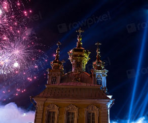 An ornate golden-domed church building lit at night with pink fireworks exploding in the background sky.