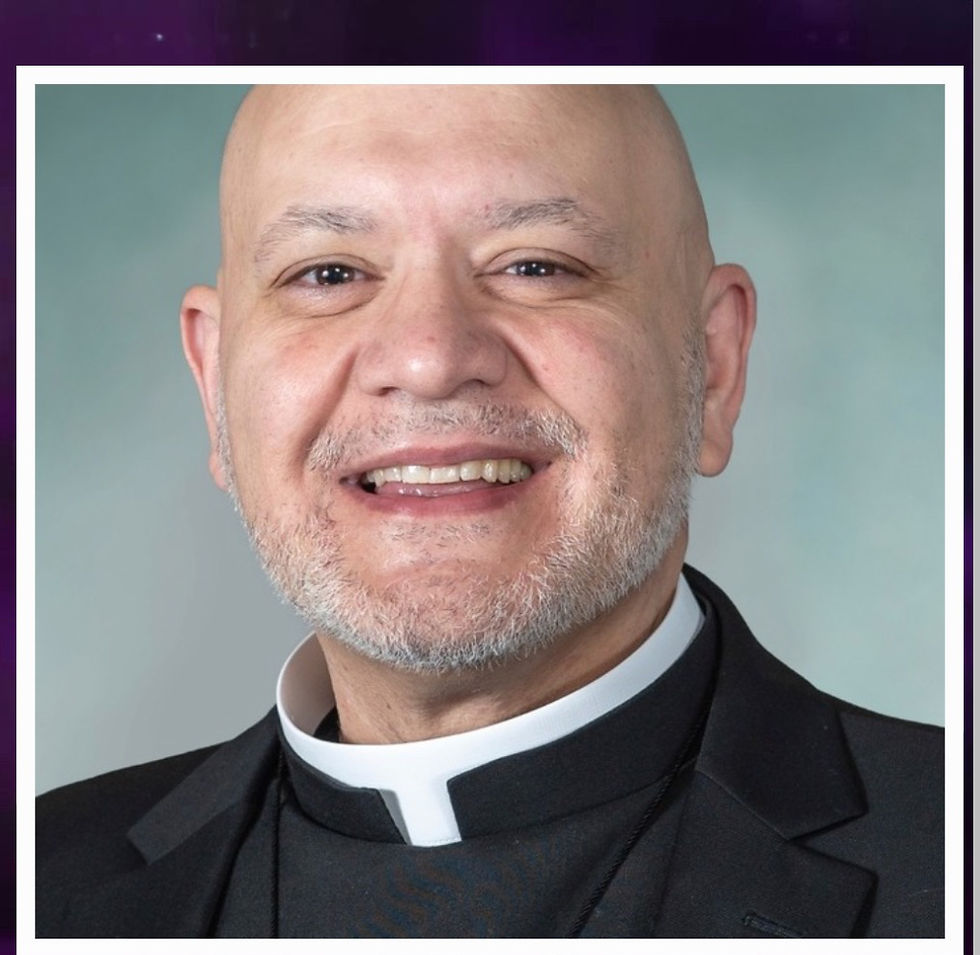 Smiling man in clerical collar and black suit against a light blue background. Celebratory and warm mood fills the image.