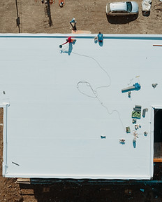 Aerial view of an apartment building with flat roof in construction, ballasted system with