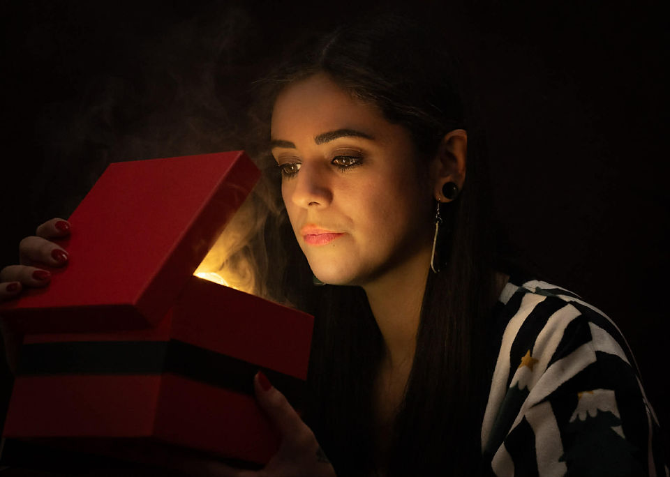 Misuzu in christmas PJs looking into a box with light and smoke emerging from it
