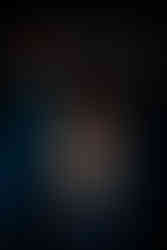 Misuzu in a blue dress with the material wrapped around her forearm and held up in front of her eyes