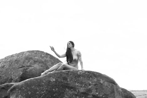 Misuzu sat nude on a rock reaching towards the sky in monochrome