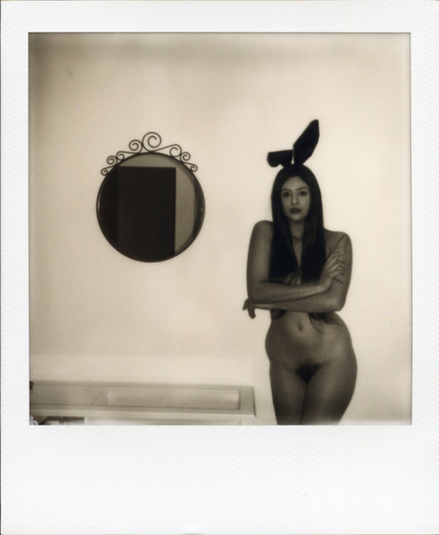 A monochrome Polaroid of Misuzu, nude with bunny ears next to a circular mirror