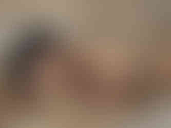 Portrait of Misuzu lying on her front surrounded by brown paper, half of her face obscured