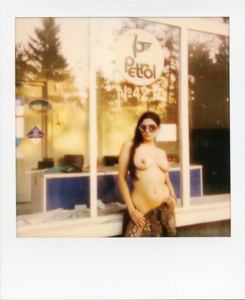 A Polaroid of Misuzu topless in an abandoned petrol station, wearing sunglasses