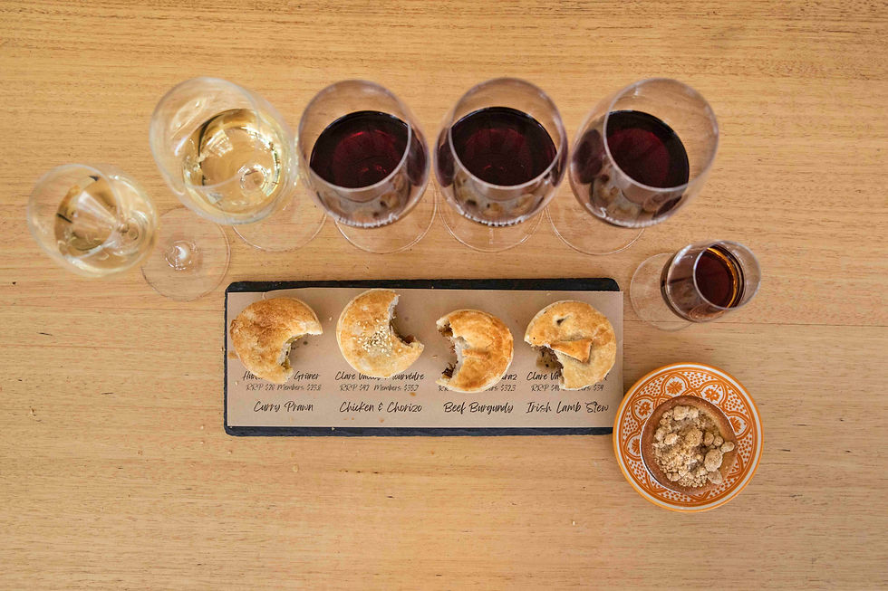 Overhead view of wine and pie tasting on a wooden table, with labels for curry prawn, chicken chorizo, beef burgundy, and Irish lamb stew