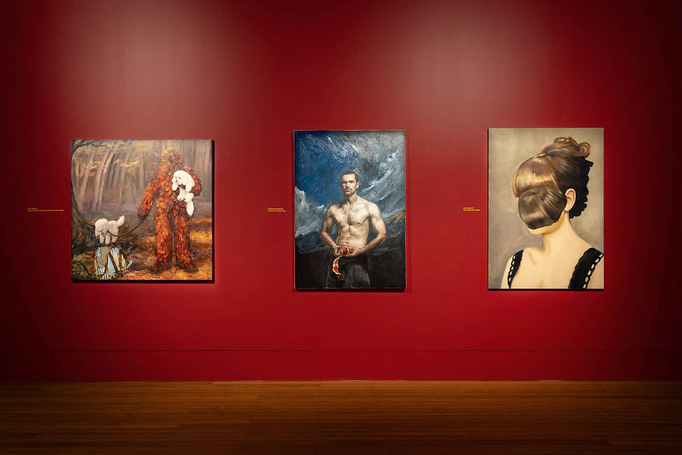 Three surreal portraits hang on a deep red gallery wall above a wooden floor, each with small unreadable labels.
