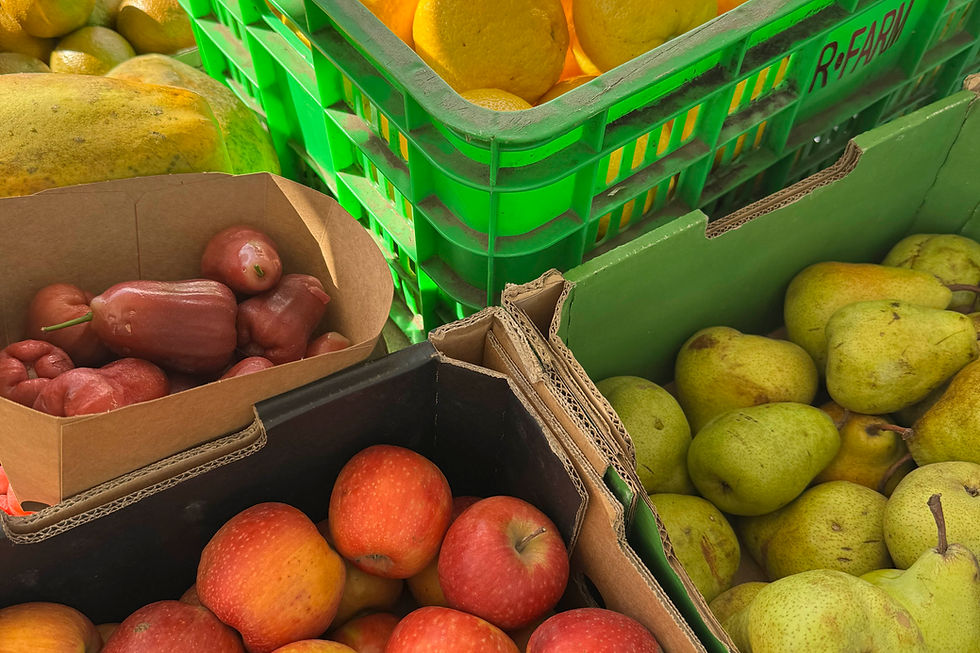 Colorful crates of pears, apples, and red wax apples at a market, with partial text R.EAR on a green crate.