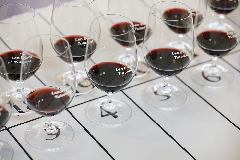 Red wine glasses labeled "Len Evans Tutorial" arranged on a grid with numbers visible underneath, creating a refined and organized display.