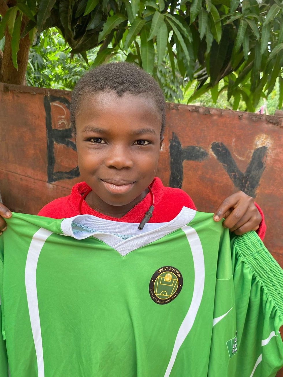 Young boy holds up a green football shirt that has been donated.