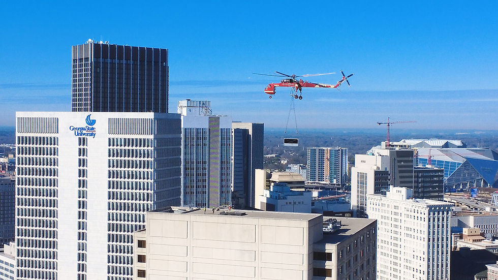 Drone photo of a Siller helicopter lifting a section of cooling tower to the top of a 20-story building.