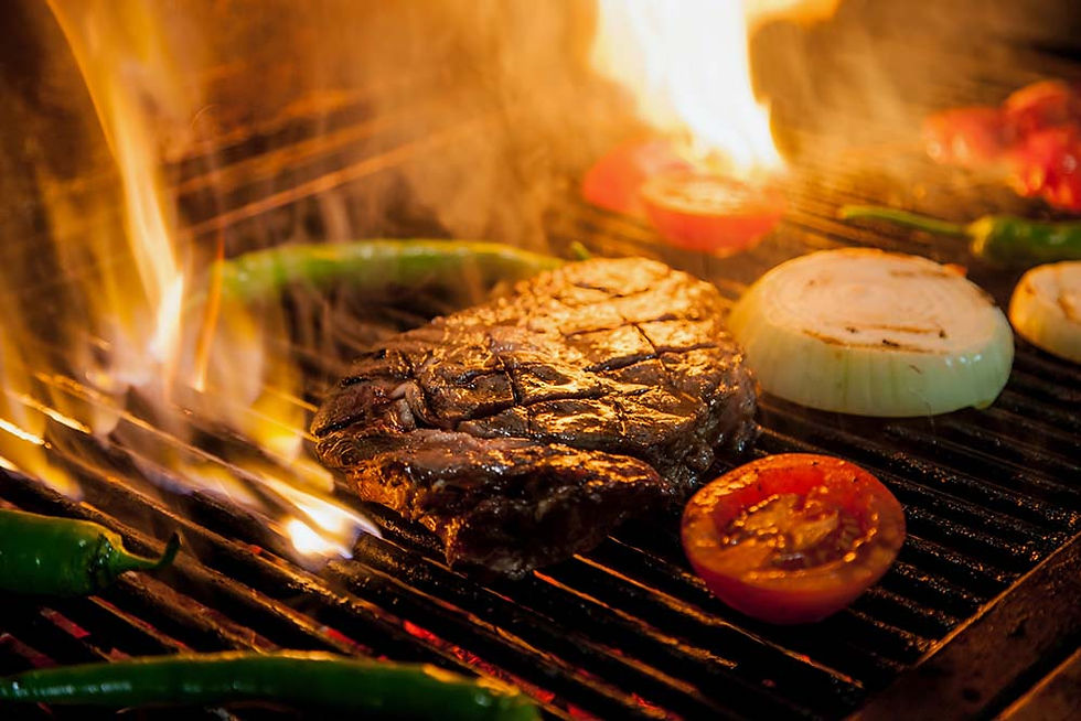 Yummy steak, tomato and onion sizzling on a fiery grill.