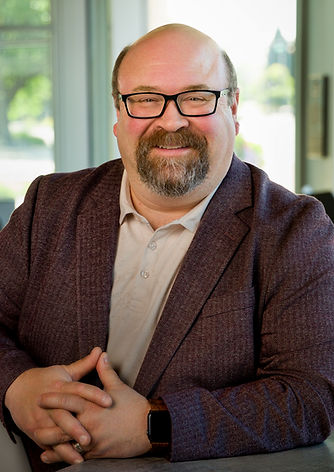 Photo of a man with glasses in a black suit