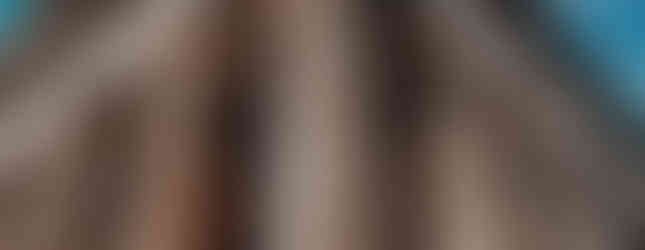 A close-up, low-angle view of the Temple of Hephaestus in Athens, Greece, showcasing its towering Doric columns and intricate friezes against a clear blue sky. The weathered marble and detailed carvings highlight the temple’s ancient craftsmanship, making it one of the best-preserved temples from classical antiquity.