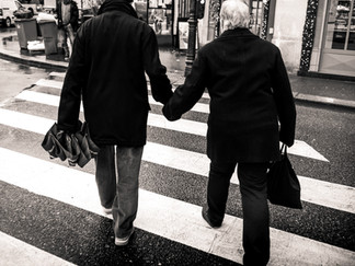 Un couple âgé se tient par la main dans la rue