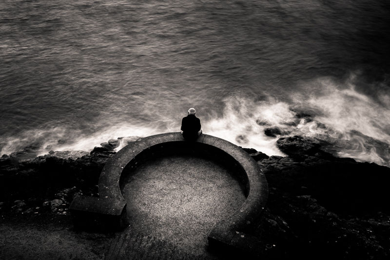 Vieil homme qui regarde assis face à la mer