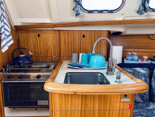The Galley - Features an oven, two-burner propane stove top, refrigeration unit, and sink.