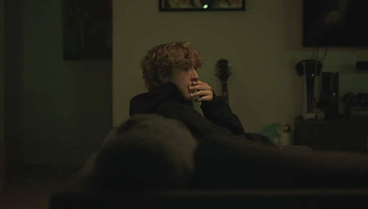 A stressed man sitting on a couch in a horror short film.