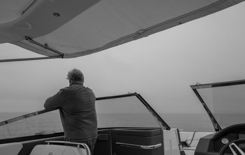 A man standing on a boat, looking out over the ocean.