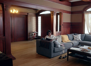 Older woman sitting on grey couch flips through a photo book.
