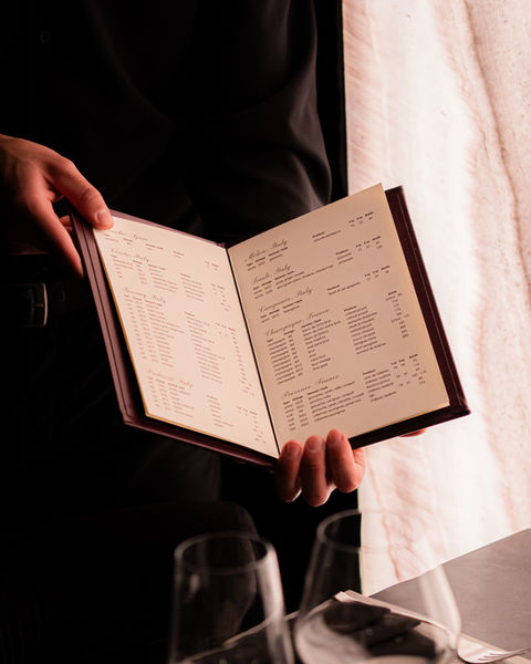 Server presenting a curated menu at The Grotto private dining room.