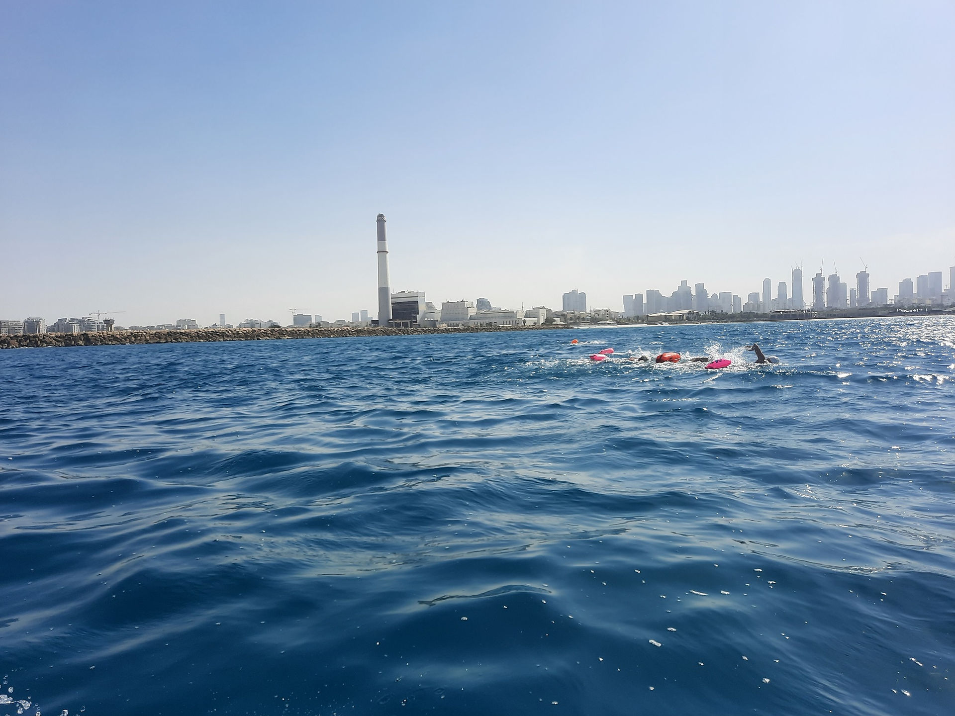 Swimmers in the Mediterranean, passing the Tel Aviv port and the Reading power station.