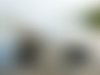 Person in yellow shirt relaxing on a wooden dock, gazing at a calm lake surrounded by trees. Peaceful and serene mood.