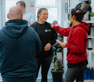A group photo of a female coach and two other members, showing her smiling as she interacts the communmity of memebrs at the end of a session.