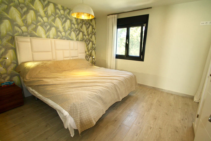 Double bed facing large window with outdoor greenery.