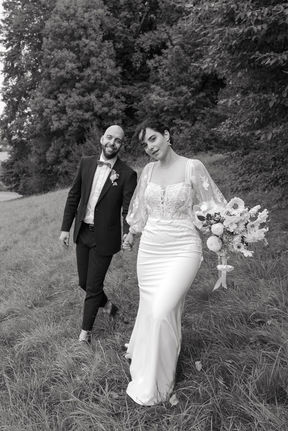 Hochzeitsbild vom Brautpaar welches über eine wiese läuft