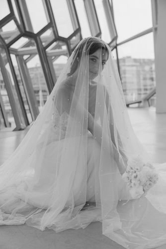 Braut in der hocke mit einem Schleier über den ganzen Koerper