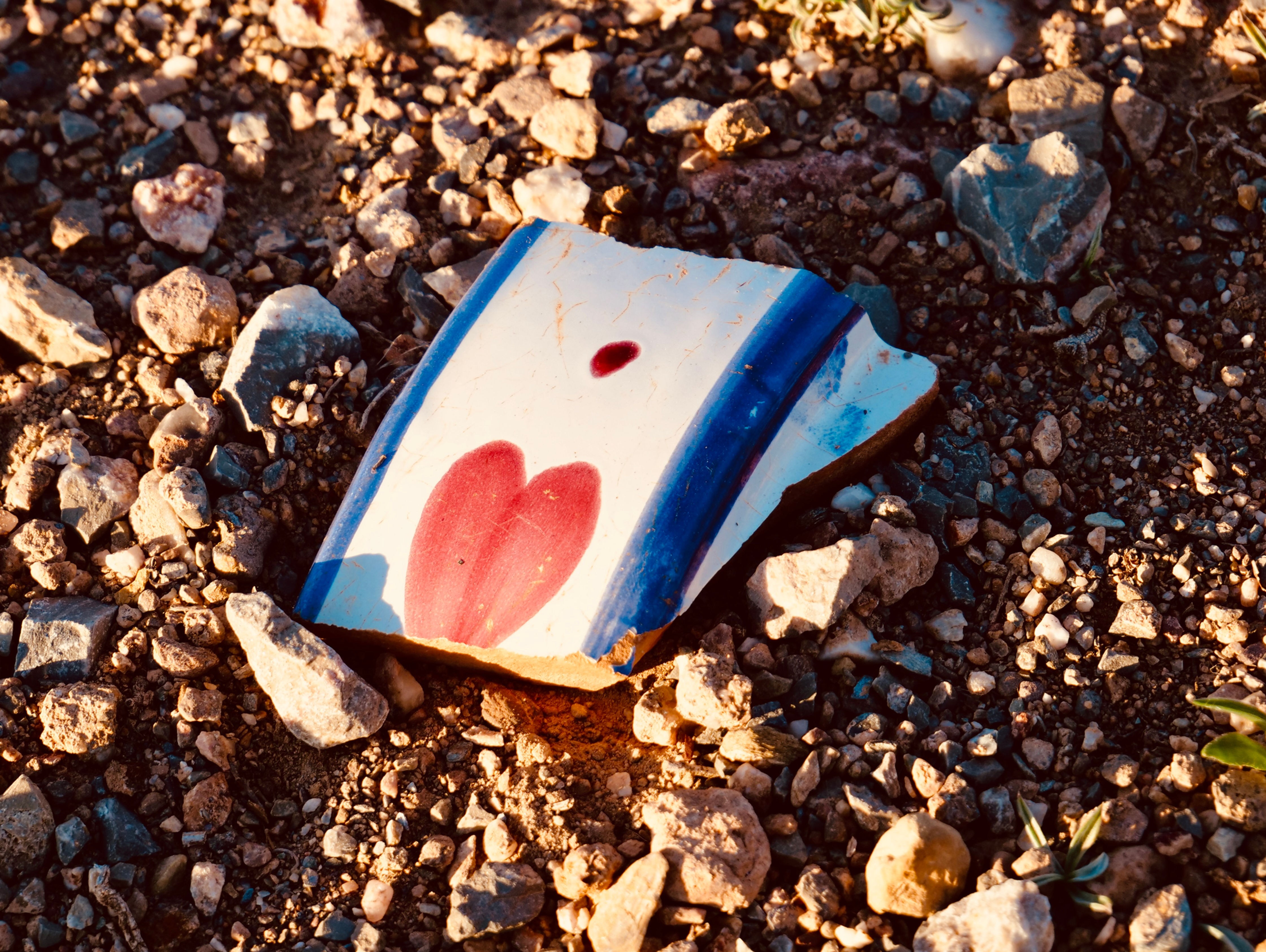 Scherbe einer Tasse mit Herz Aufdruck am steinigen Boden