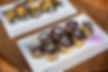Gourmet eggplant rolls with creamy herbed cheese filling and purple onion flowers on white plates, placed on a wicker surface.