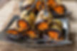 Eggplant rolls stuffed with bright orange Soviet-Korean style marinated carrots on a square plate. Two forks rest on top. Background features woven fabric.
