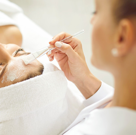 Woman enjoying facial treatment at beauty parlor or spa salon. Professional beautician hol
