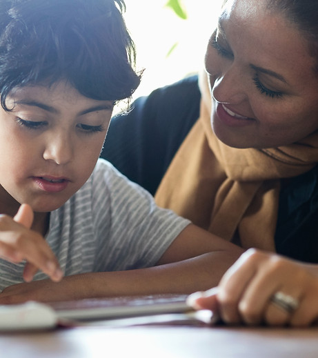young boy getting reading help from a child care provider