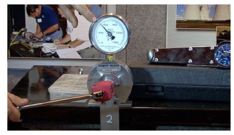 A meter illustrates the clamping force of a torque wrench on a threaded fastener.