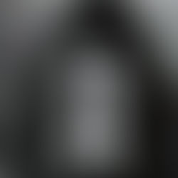 Black and white photo of dark haired woman with half of face reflected in mirror