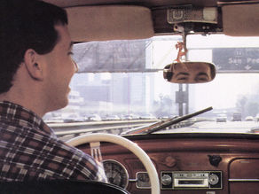 Man in flannel shirt driving car under highway sign