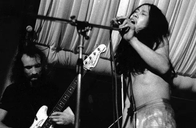 Black and white photo of long-haired Japanese man on stage