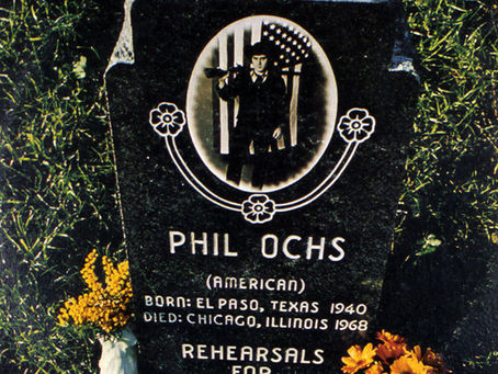A black headstone featuring a gun-toting man in black stood in front of an American flag, with yellow flowers