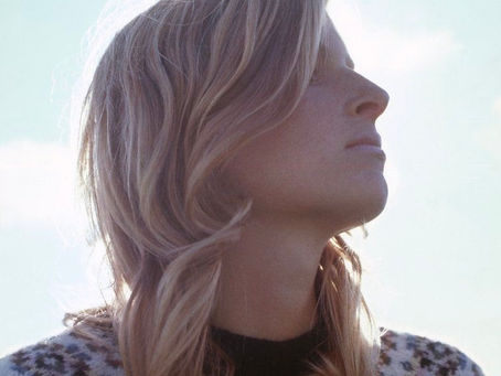 Blonde woman in sweater against blue sky