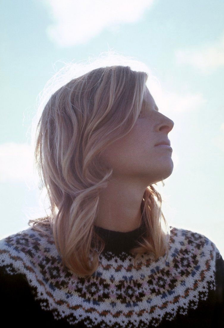 Blonde woman in sweater against blue sky